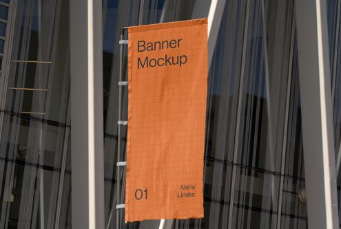 Vertical banner mockup hanging on building facade in urban setting, ideal for presenting outdoor advertising designs.