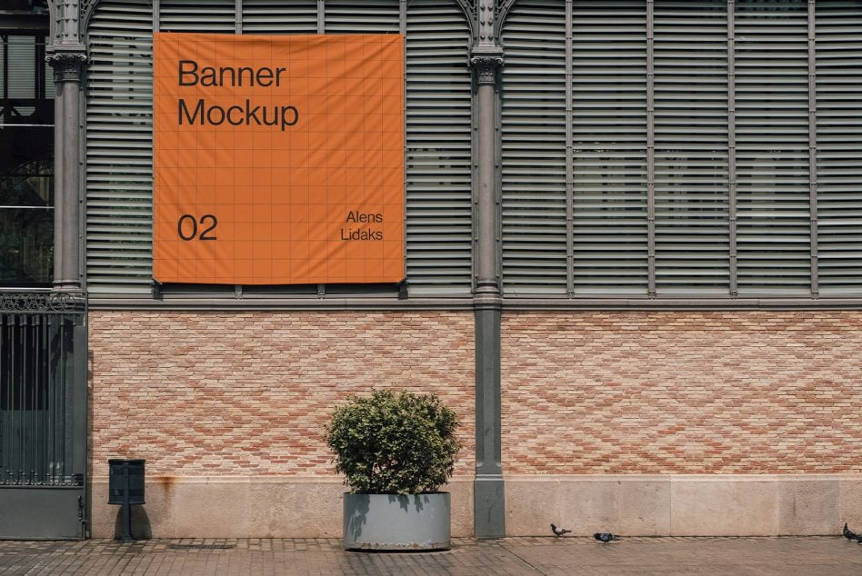 Orange fabric banner hanging on building facade with metal columns between brick