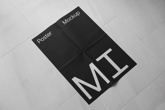 Folded black and white poster mockup with modern typography on a textured floor, ideal for showcasing design work.