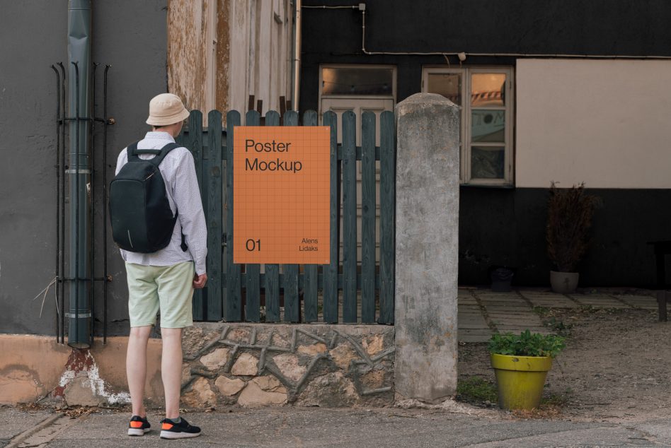 Person standing by a street fence with urban poster mockup, ideal for designers to showcase outdoor advertisement designs.