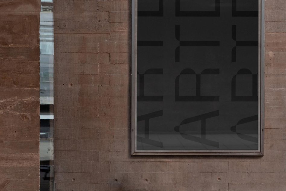 Dark storefront window in red brick wall with geometric shapes visible through glass