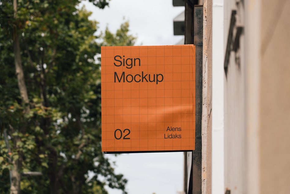 Orange hanging sign mockup on building corner with trees, natural daylight