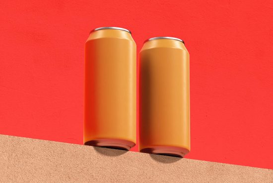 Two blank gold aluminum cans on red and tan background for mockup design, ideal for beverage packaging presentations and branding.