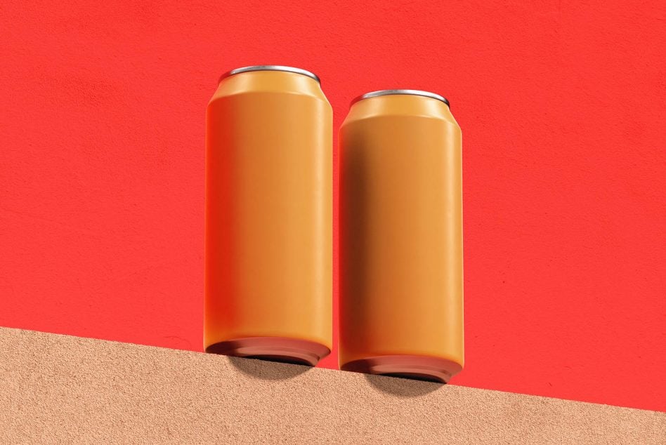 Pair of golden cans sitting on sand dune with vibrant red sky behind them