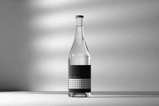 Minimalist clear glass bottle mockup with black label design on a bright background with subtle shadows, ideal for branding and packaging presentations.