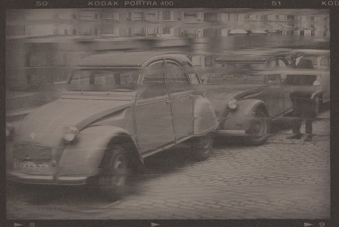 Vintage sepia photo of classic cars and a man in motion on cobbled street, old-style image for mockups, retro graphics, and nostalgic designs.