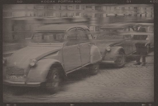 Vintage sepia photo of classic cars and a man in motion on cobbled street, old-style image for mockups, retro graphics, and nostalgic designs.