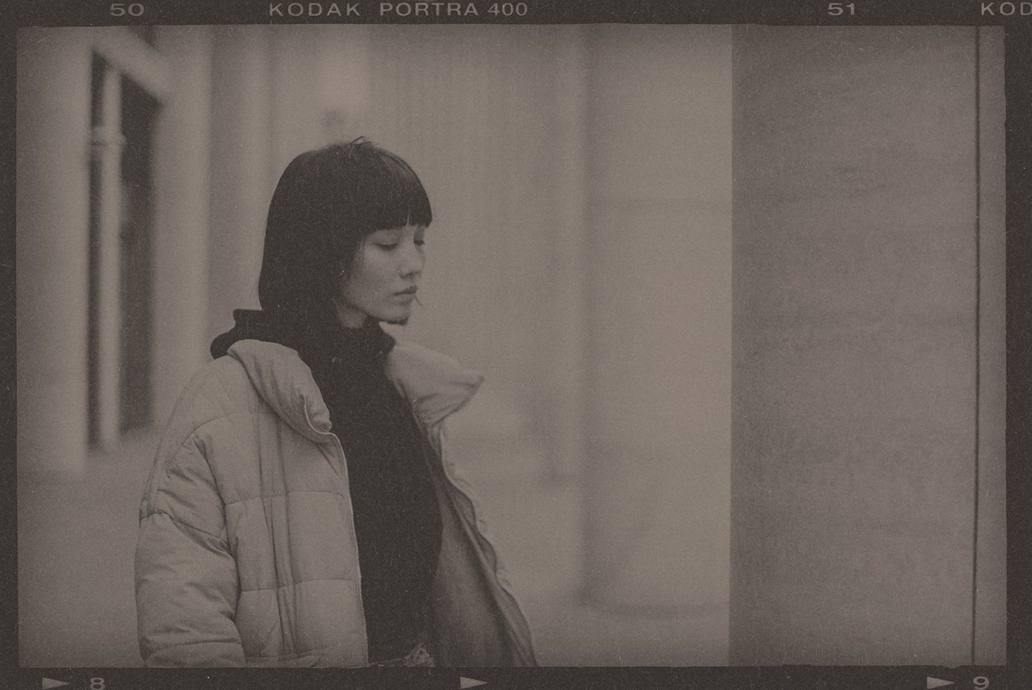 Vintage style photo of a pensive woman in urban setting, film grain effect, ideal for graphic design or template background.