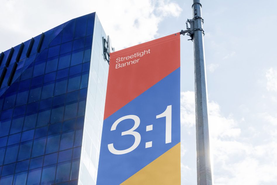 Multi-color blocked streetlight banner on metal pole near office tower