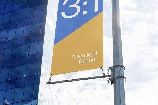 Urban streetlight banner mockup against a blue sky and glass building facade for outdoor advertising design presentations.
