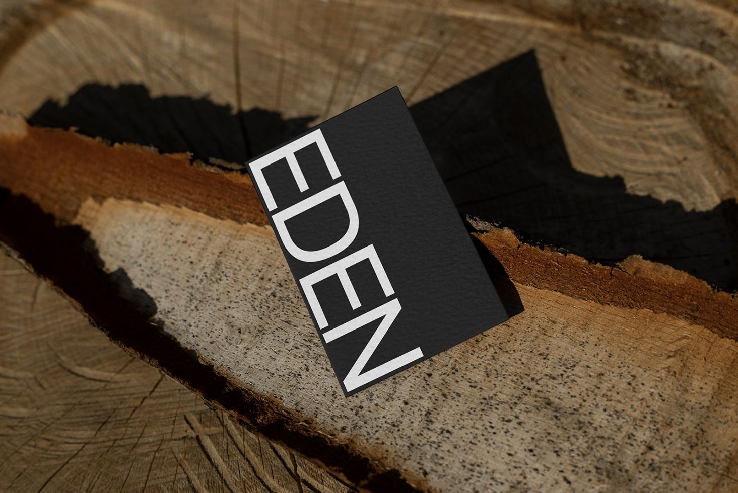 Business card mockup with modern typography on textured wood background, showcasing elegant design for branding identity.