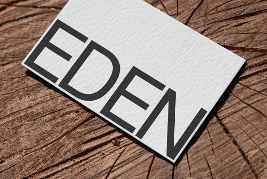 Elegant business card mockup with bold typography lying on textured wood surface, ideal for designers looking to showcase branding identity.