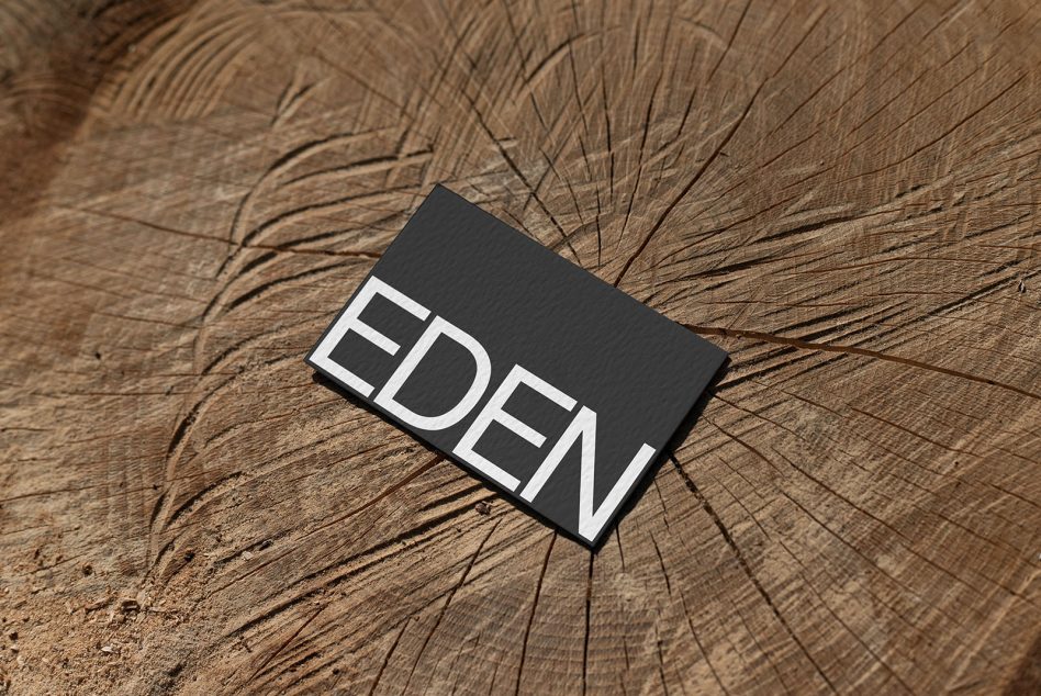 Business card mockup with black textured design on a wooden background, showcasing font and branding for designers.