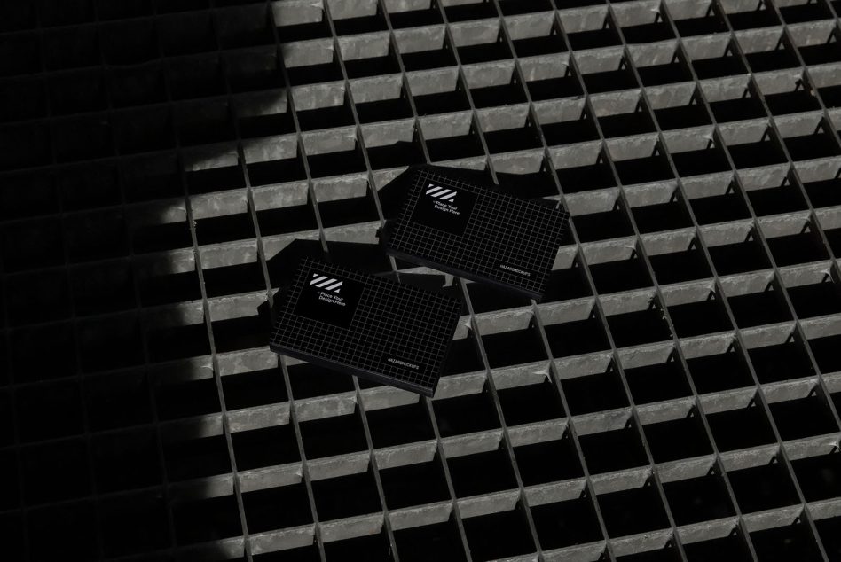 High-contrast black business cards with grid design mockup on textured metal surface, ideal for corporate identity design presentations.