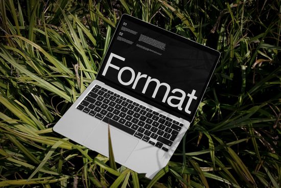 Laptop on grass displaying bold font typeface, ideal for designers looking for mockups, graphic design, typography inspiration, and digital assets.