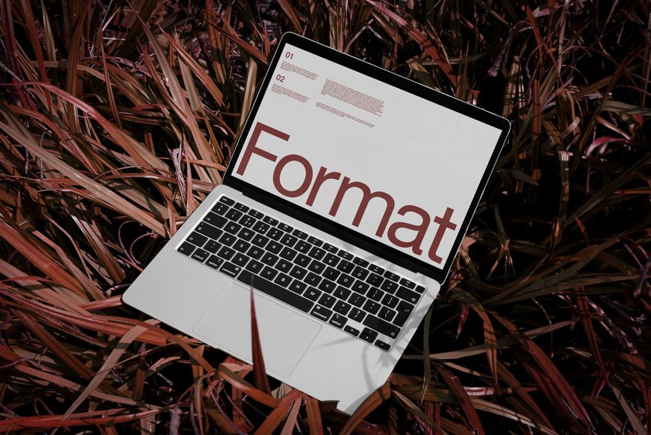 Laptop on foliage displaying bold font design mockup for digital graphics, creative assets, typography presentation, designers portfolio.