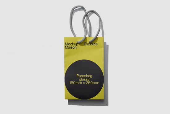 Yellow and black glossy paper bag mockup with grey rope handles on a clean white background, perfect for presentations and branding.