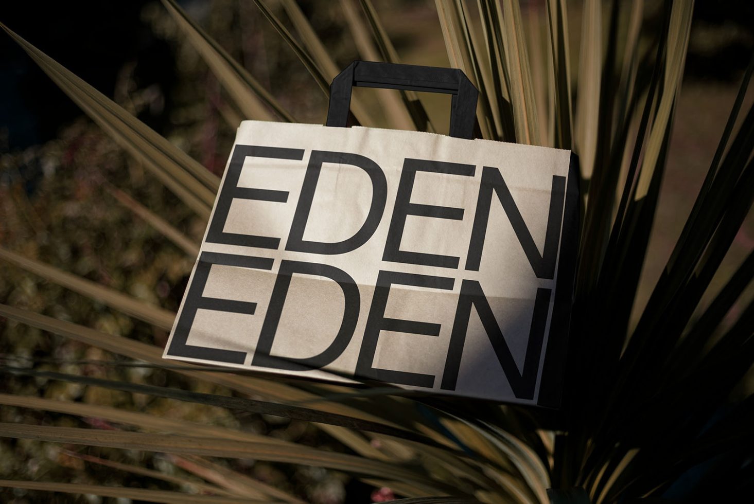 Tote bag mockup with bold 'EDEN' design against natural background, ideal for showcasing branding and graphic designs.