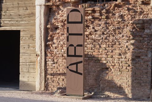 Modern font design displayed on tall banner stand against rustic brick wall setting, showcasing innovative typography for graphic designers.