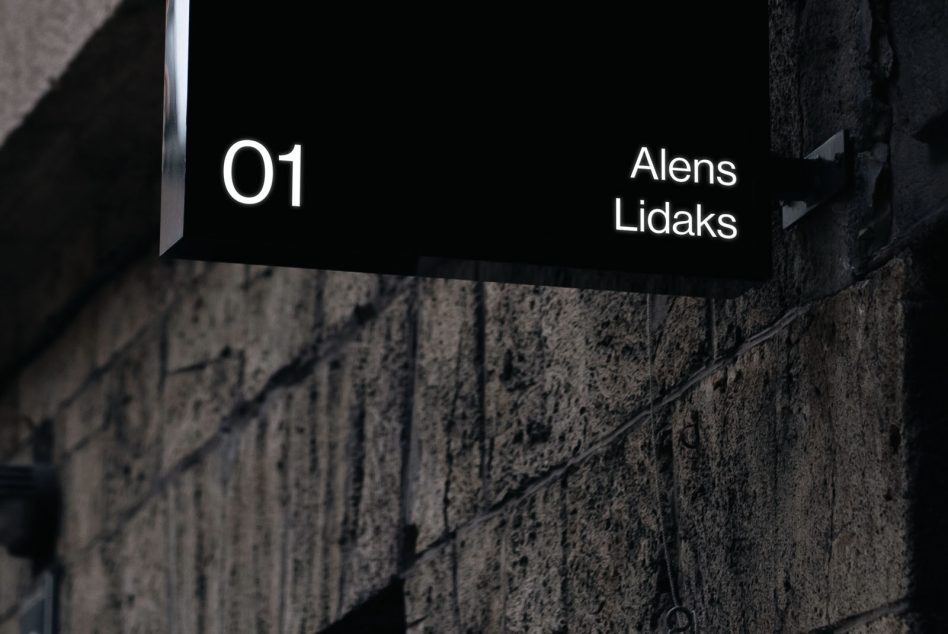 Illuminated metal sign on concrete wall at night showing signage mockup