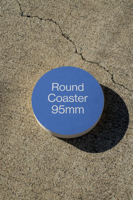 Blue round coaster mockup on concrete surface with text overlay for product design display and realistic shadow, suitable for graphic designers.