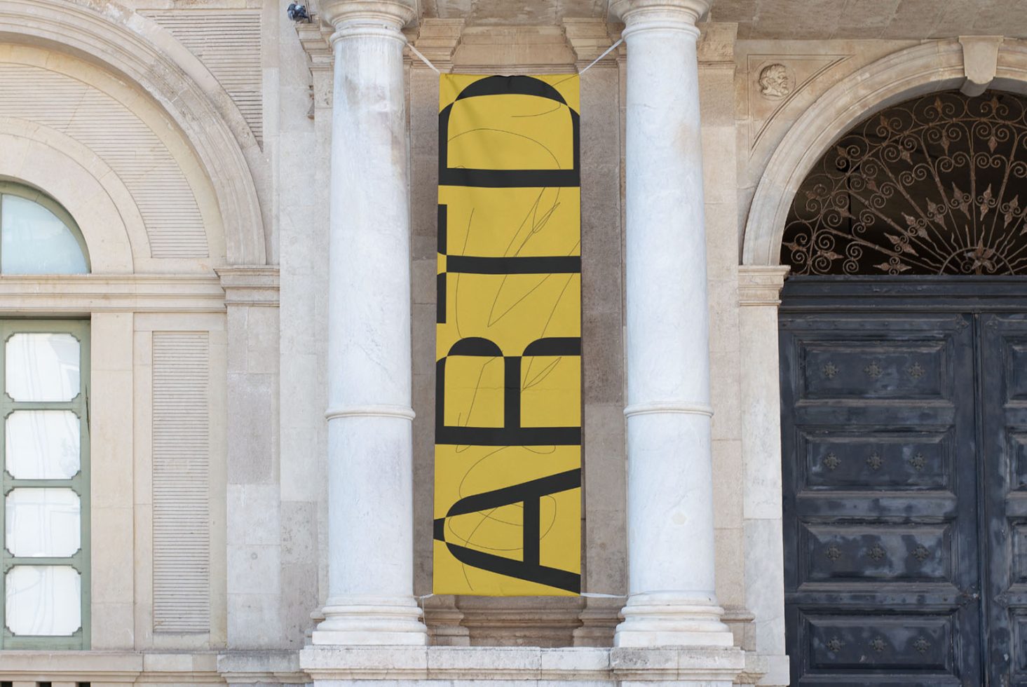 Vertical banner mockup hanging between pillars on a classic building facade, displaying abstract graphics, ideal for presentations and portfolio.