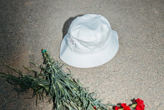 White bucket hat on concrete with greenery, ideal for fashion mockups, accessory templates, and urban summer apparel graphics design.