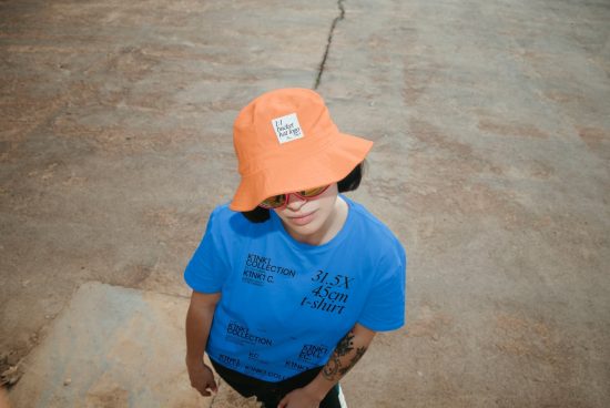 Person wearing vibrant orange bucket hat and blue t-shirt with text design, ideal for fashion mockups, urban streetwear templates.