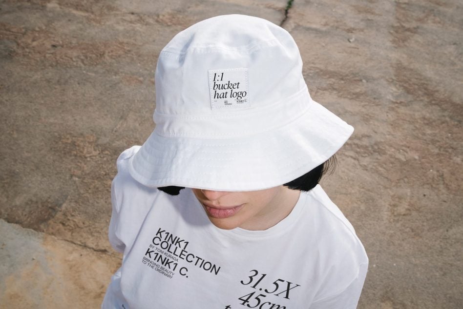 White bucket hat with woven label on concrete background, overhead shot