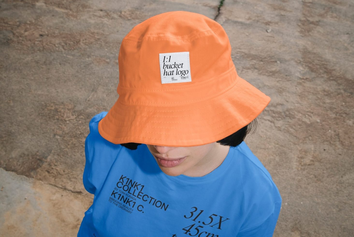 Person wearing vibrant orange bucket hat with logo mockup and blue shirt, ideal for designer mockups, apparel branding, and fashion presentations.