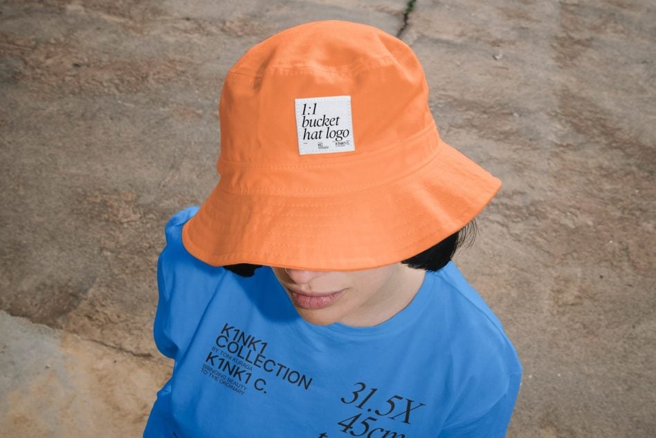 Bright orange bucket hat with woven label on concrete background