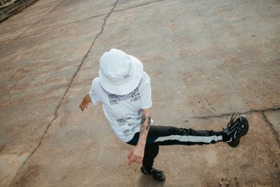 Dynamic urban streetwear fashion mockup featuring a person in a white bucket hat and graphic t-shirt with trendy trousers and sneakers.