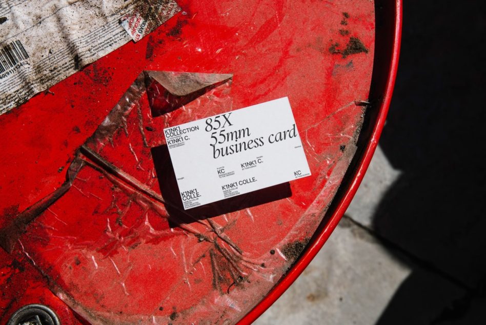 Business card mockup on a textured fire-red surface with shadow play, ideal for presenting design work to clients.