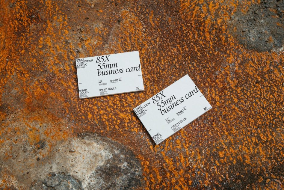 Two business cards on rusty orange concrete background flat lay