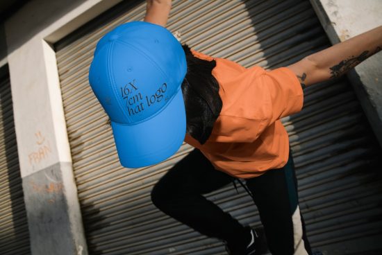Dynamic mockup of a blue snapback hat worn by a person with urban background, showcasing space for a customizable logo design.
