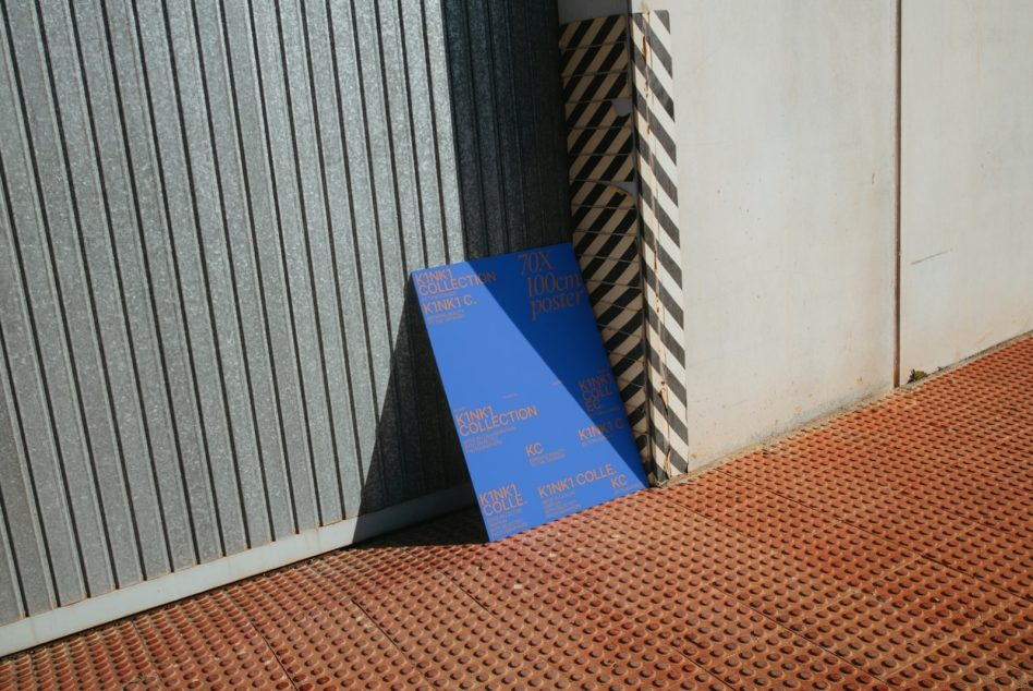 Blue K1NK1 poster mockup in industrial corner setting with metal backdrop