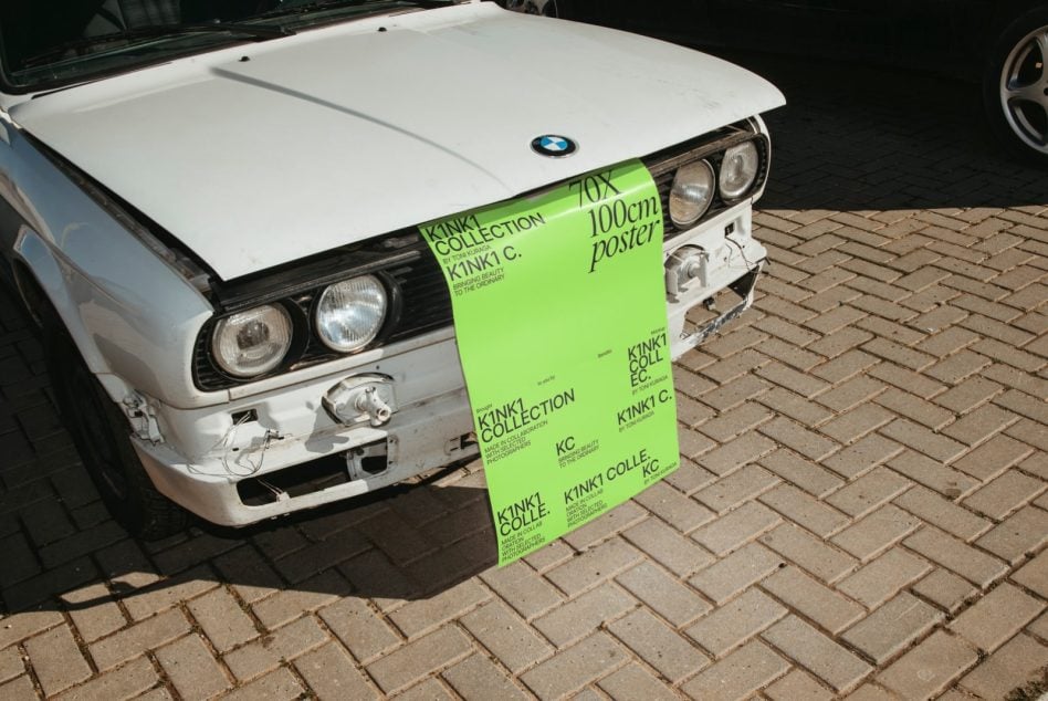 Lime green K1NK1 poster on classic car with brick surface below