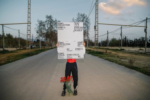 Person holding large poster mockup in outdoor setting, ideal for showcasing design work, suitable for graphic displays and advertising mockups.