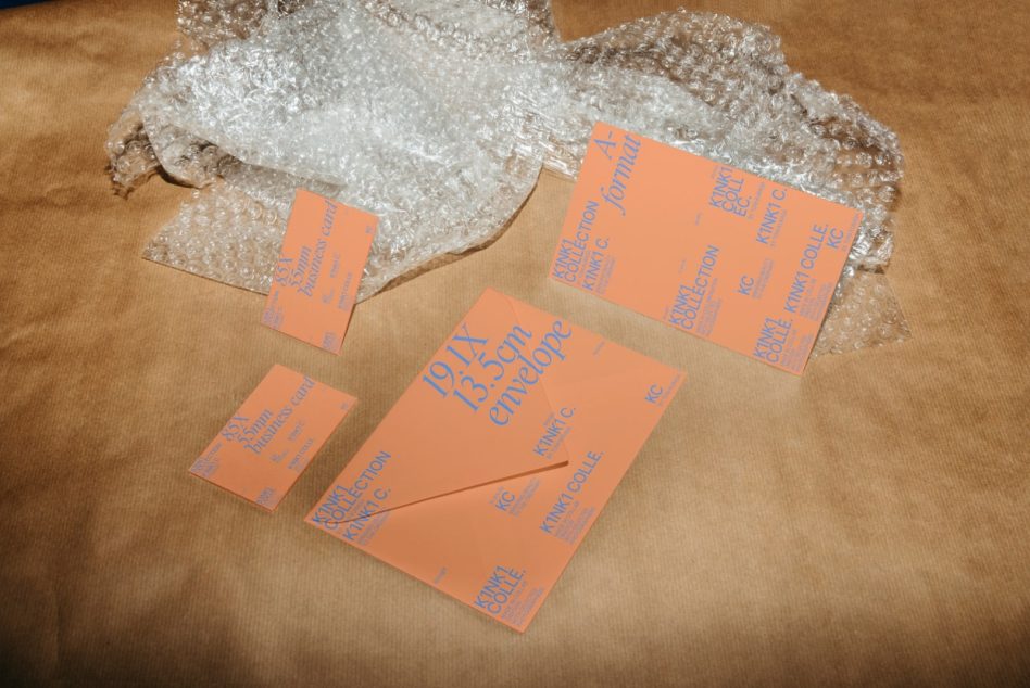 Orange business card, envelope, letter set spread on bubble wrap over tan fabric