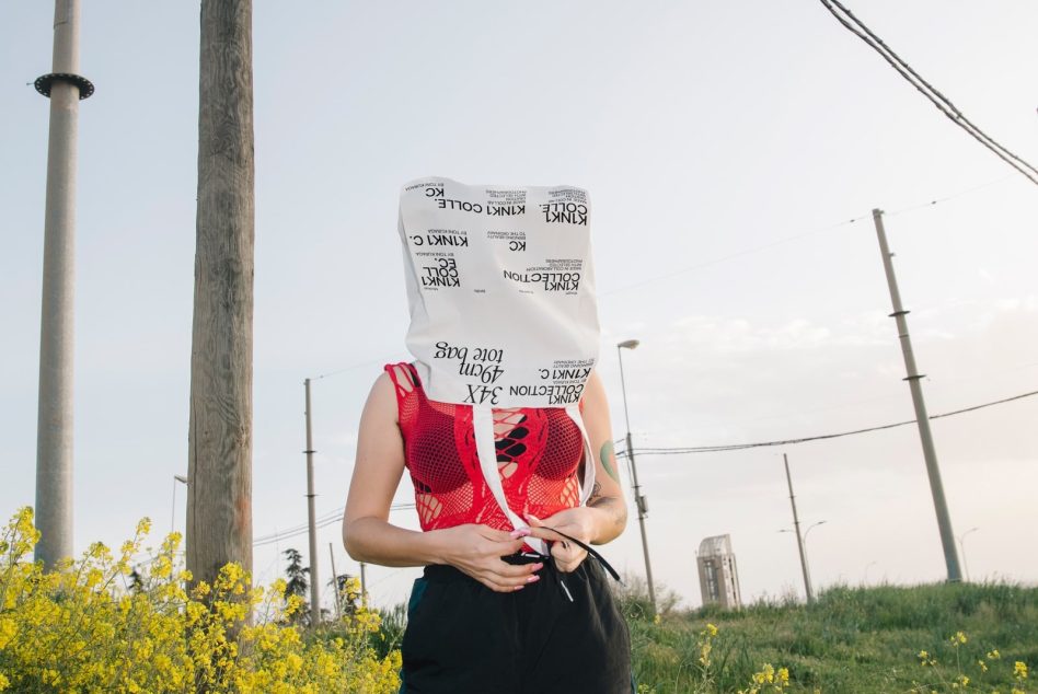 Person with graphic print fabric over head in field for edgy design mockup, creative outdoor portrait concept, unique fashion presentation.