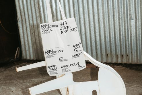 White tote bag with black text on a modern chair, industrial background, design mockup, clean and contemporary style for presentations.