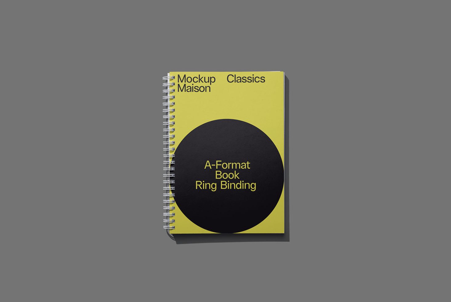 Spiral notebook mockup with yellow cover and black design elements on a gray background, showcasing product design for branding assets.