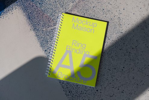 Bright yellow A5 ring binder brochure mockup on textured surface with shadows, design display, graphic print, creative template.