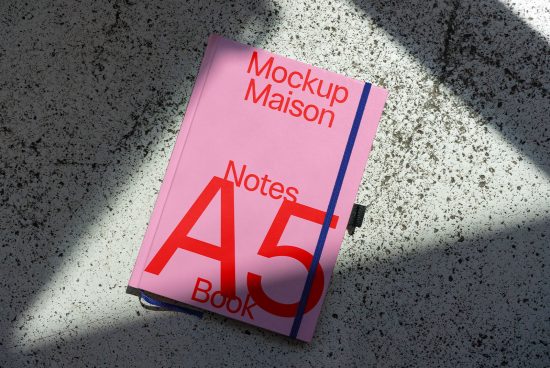 Pink A5 notebook mockup with shadow overlay on textured surface, ideal for presenting stationery designs and font showcasing.