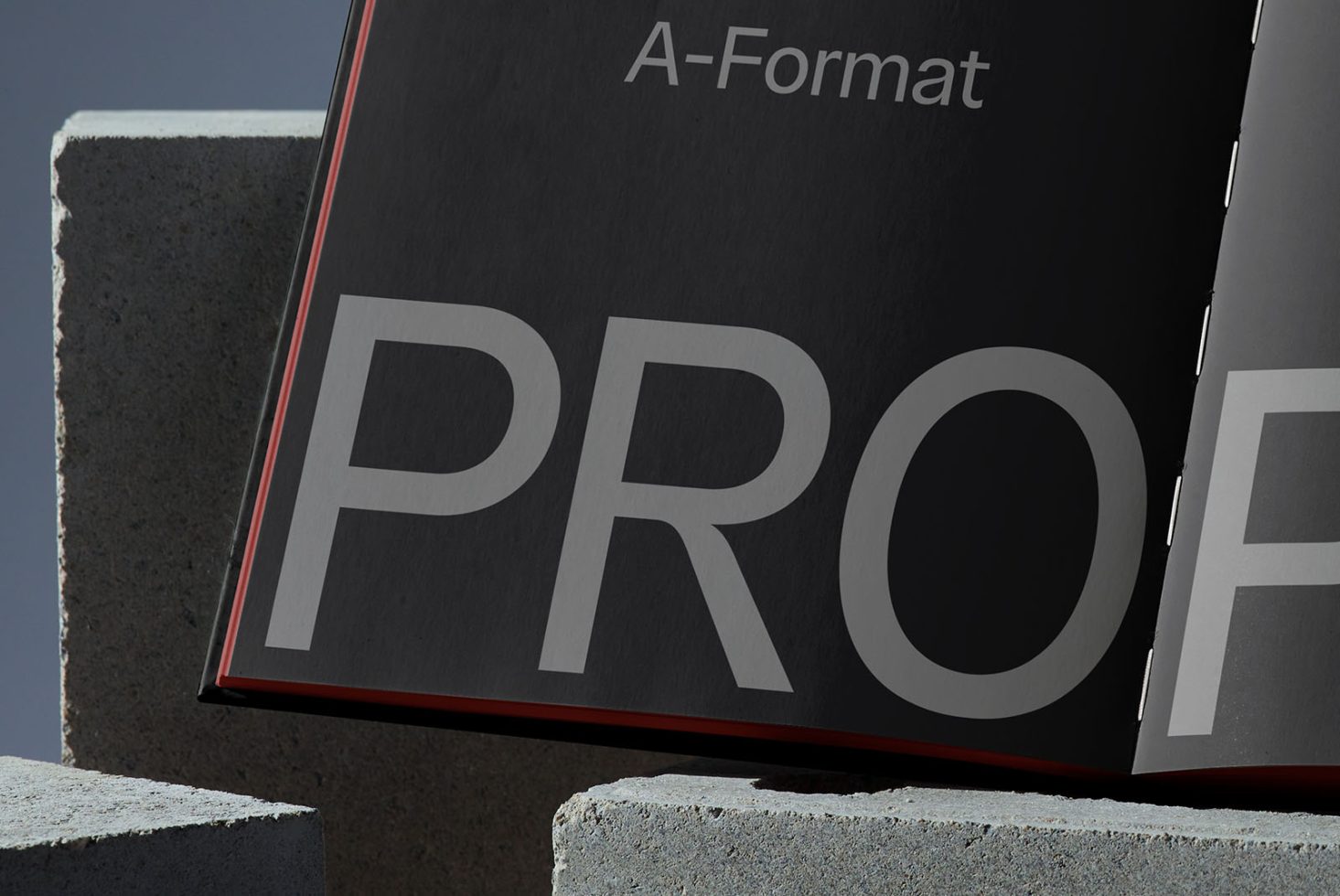 Professional black portfolio mockup with unique red spine detail on concrete blocks, conveying minimalist design presentation.