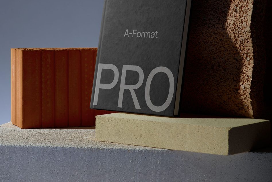 Dark hardcover book with PRO text on concrete blocks near textured brick