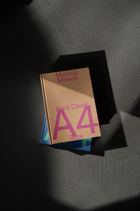 Kraft paper A4 hardcover book with magenta lettering stacked on colored books