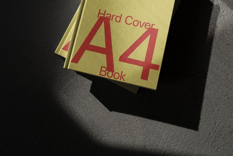 Yellow A4 book with red letters on concrete surface casting shadow