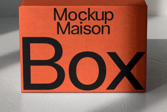 Orange box mockup with bold black typography design on a light textured background, ideal for product packaging presentations.