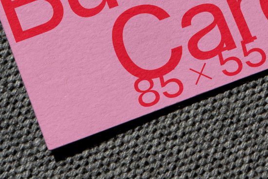 Close-up of a pink business card mockup with red typography on textured background, showcasing design detail for branding assets.